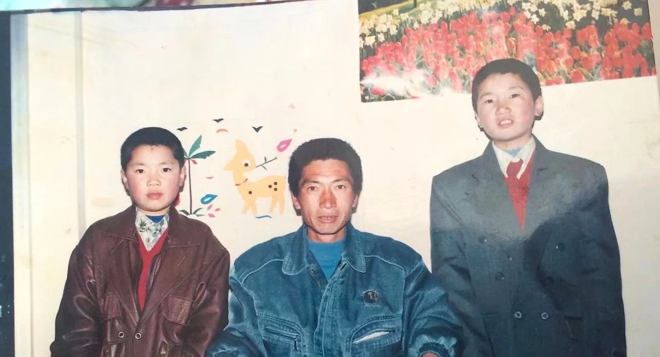 三十年前的旧照片:三个人并排站着,背景是画着小鹿和花的白墙